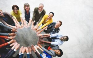 Above view of a group of people standing in a circle holding their arms out to form a circle with their hands