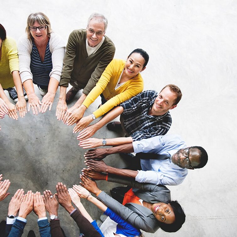 Above view of a group of people standing in a circle holding their arms out to form a circle with their hands